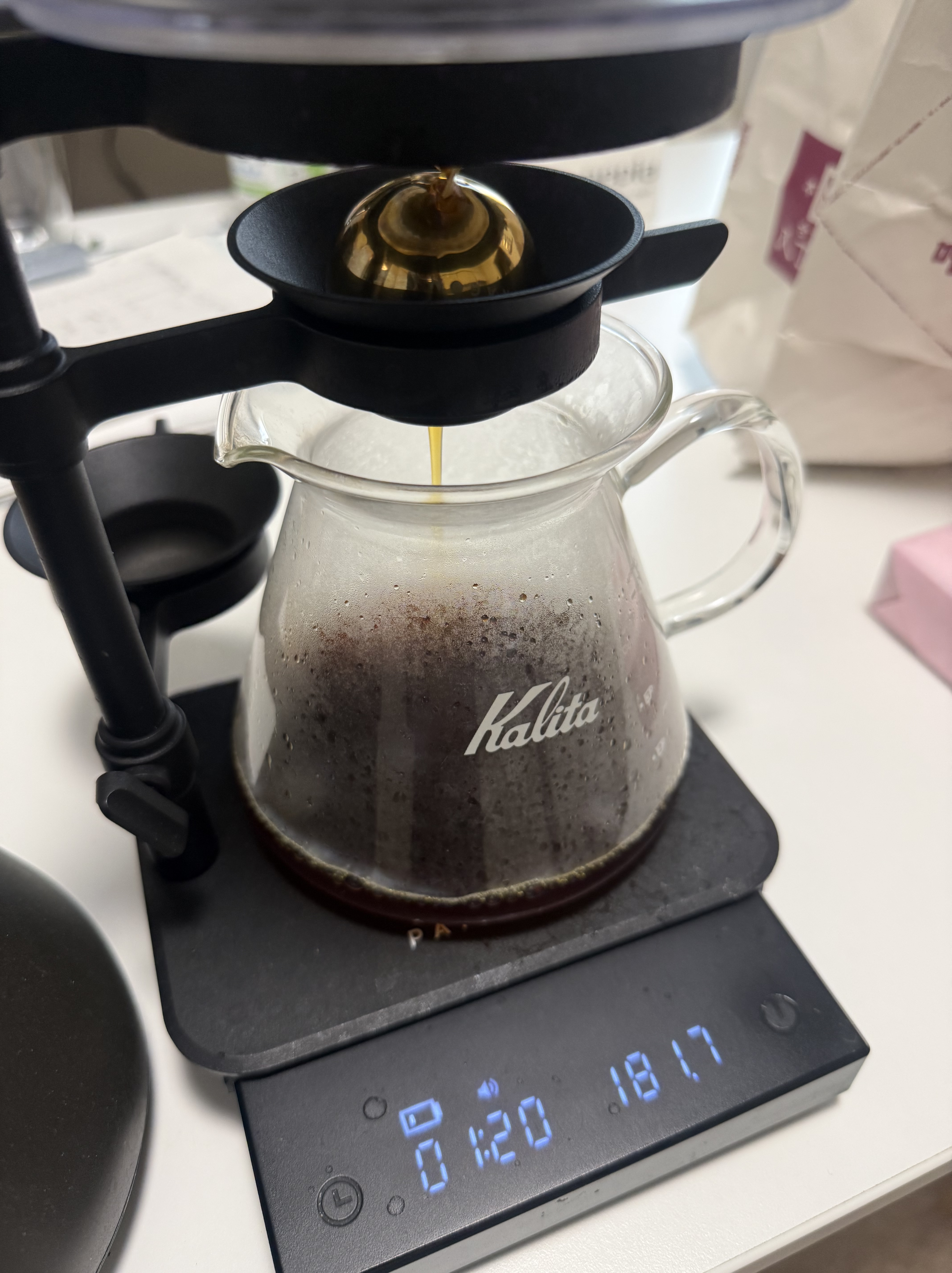 抽出したコーヒーを金色の球に当て、カリタのガラス製サーバーへ落としている様子。